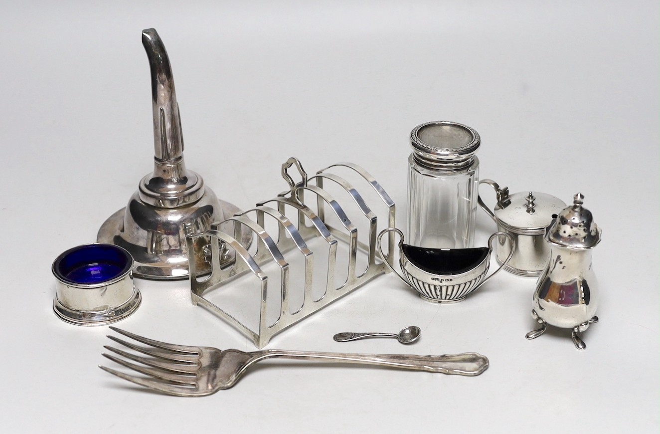 A George V silver seven bar toastrack, Birmingham, 1913, 11.9cm, four silver condiments, a silver mounted glass toilet jar and two silver plated items including a wine funnel.